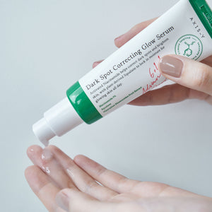 Selenaire AXIS-Y Dark Spot Correcting Glow Serum in a clear dropper bottle with serum drops on a white background